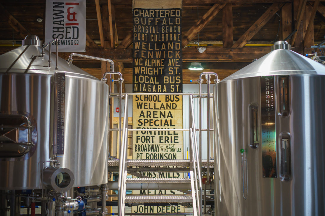 Bus destination banners hang between beer tanks as a reminder of one of the the building's many former lives as a bus maintenance and storage barn.